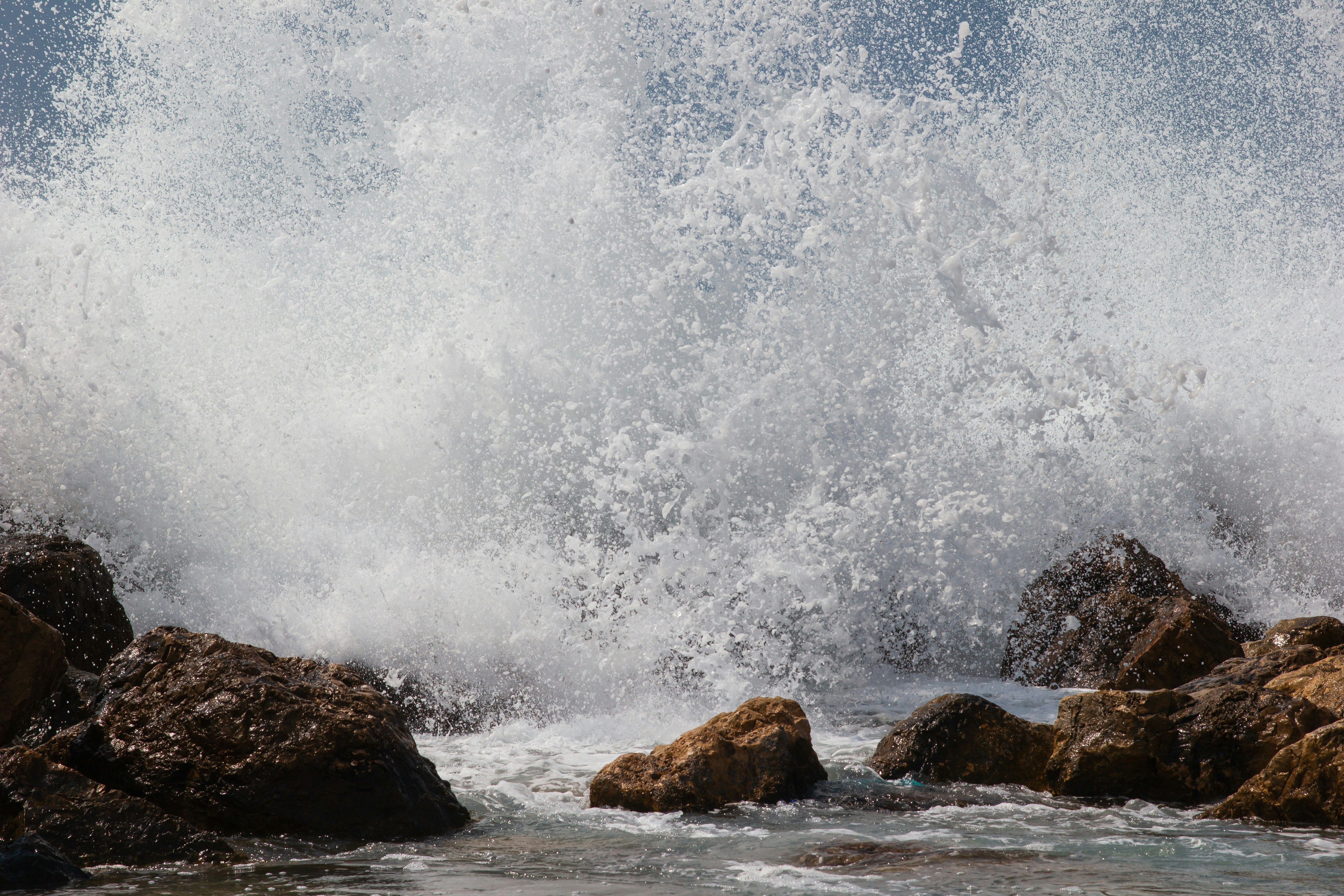 water waves hitting brown rocks